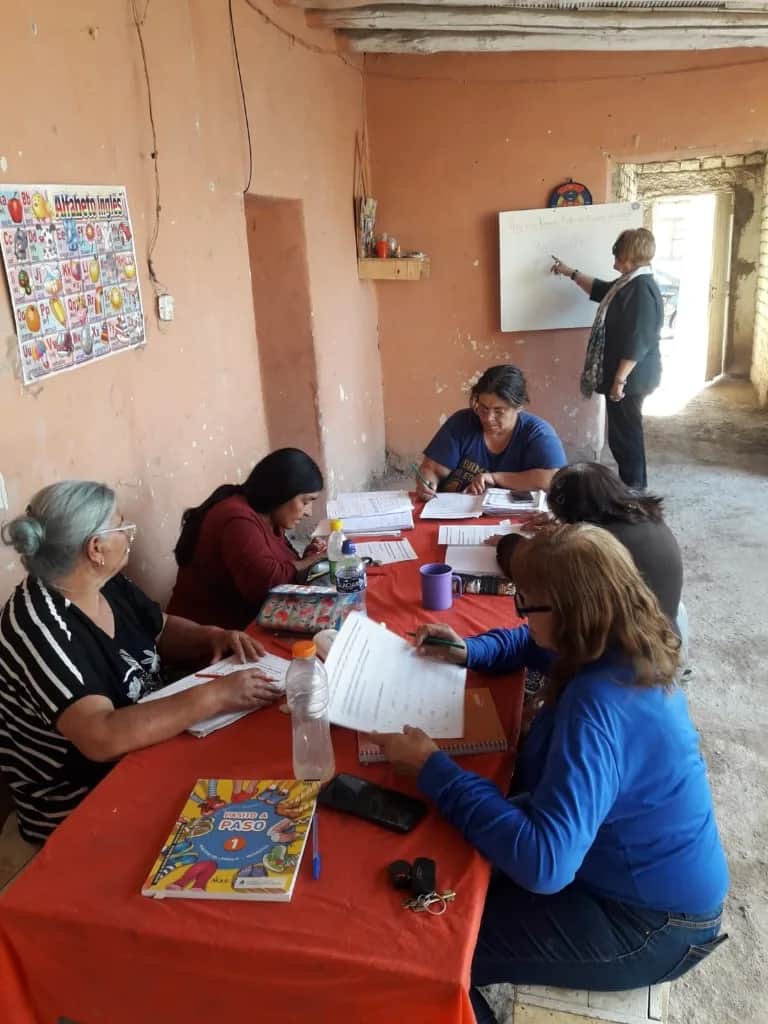 Encuentro comunitario de apoyo escolar y alfabetización: participantes trabajando en fichas y cuadernos en un espacio de barrio.